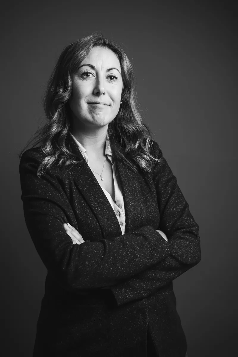 Sabrina Patalano debout, bras croisés, en veste, regard caméra, portrait noir et blanc