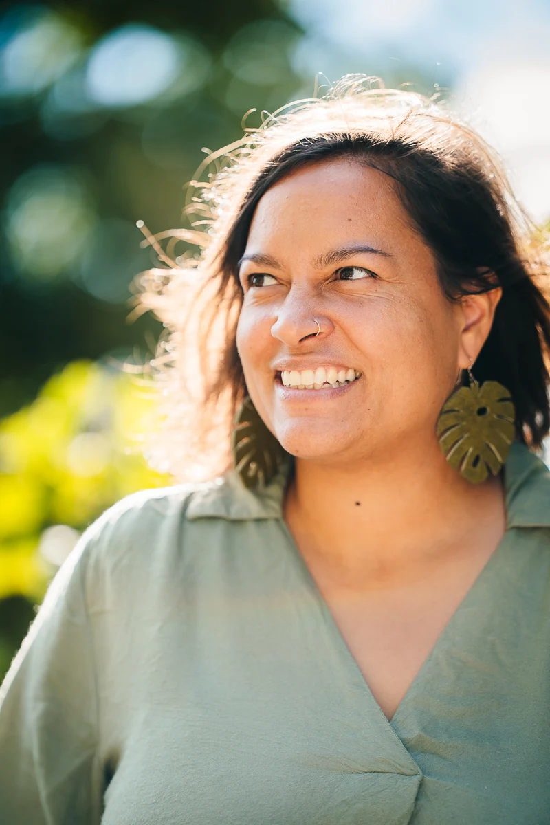 Lune Dargery, paysagiste, souriante en plein air, à contre-jour, boucle d'oreille en forme de feuille, portrait couleur